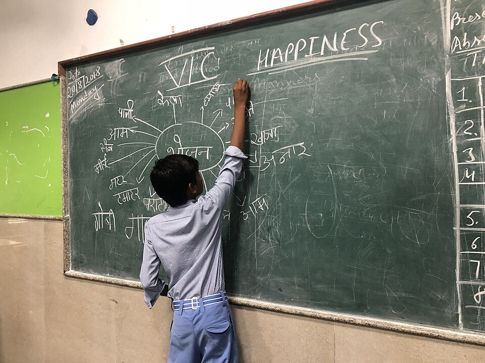 Student der Delhi Government School definiert an der Schultafel, was Glücklich sein bedeutet (Quelle: Government of Delhi veröffentlicht unter der CC ShareAlike 4.0 International)